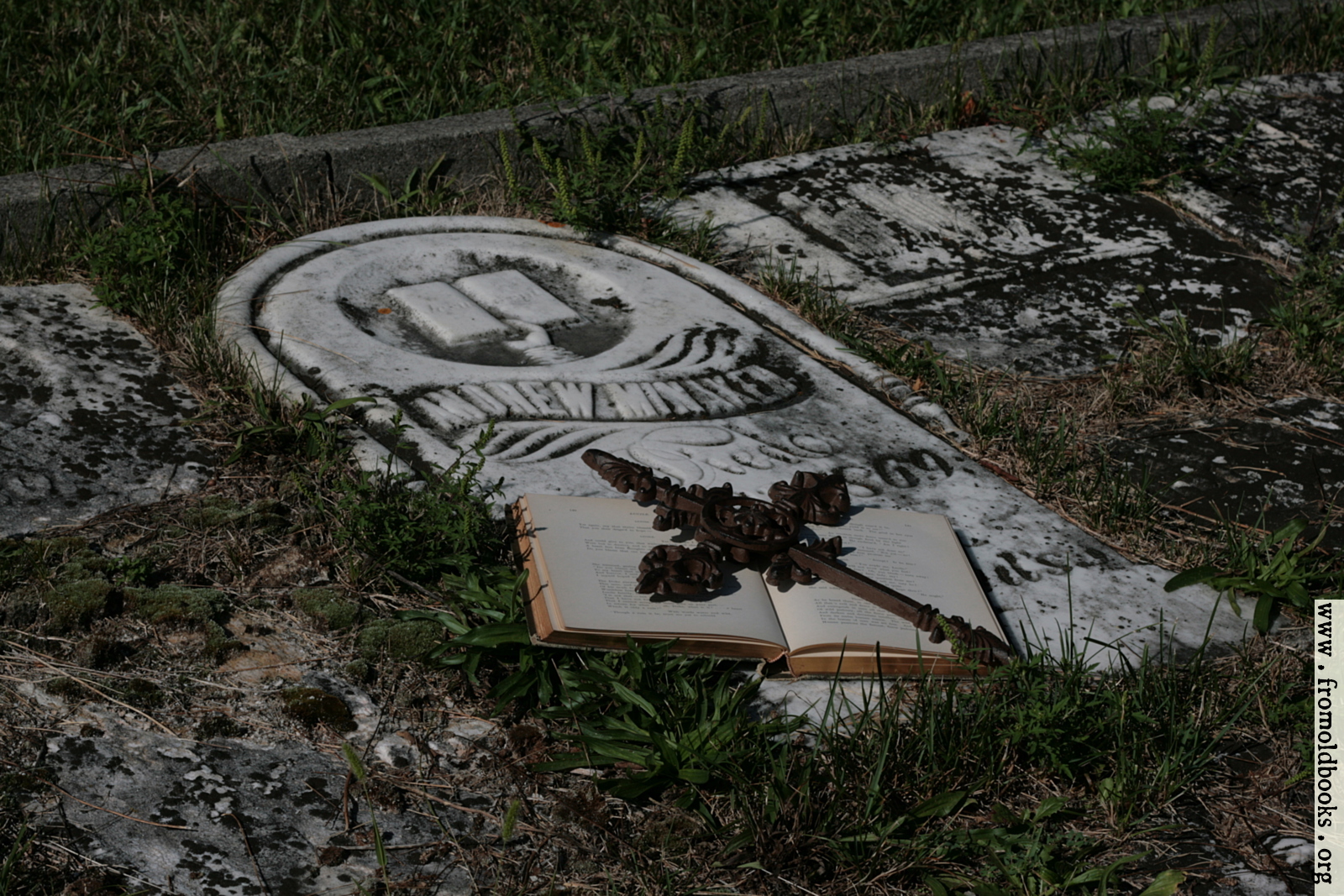 [Picture: Open book with iron cross on grave]