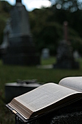 [Picture: Open Bible and cross in graveyard]