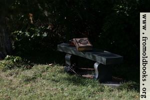 Stone bench with books and cross