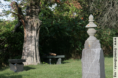 [Picture: Tombstone with benches under tree]